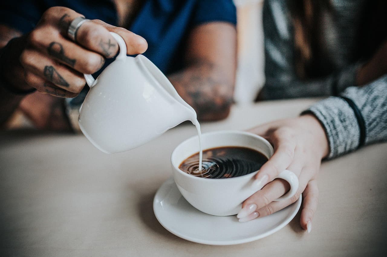Steamed milk being poured into a cup of coffee