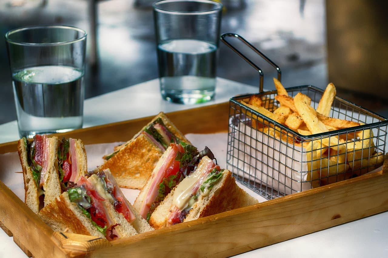 Toasted sandwiches and a basket of chips on a wooden tray